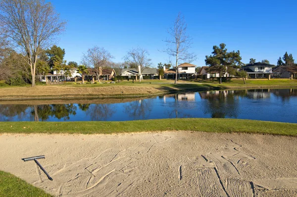 Sand bunker på golfbanan med grönt gräs, träd och damm — Stockfoto