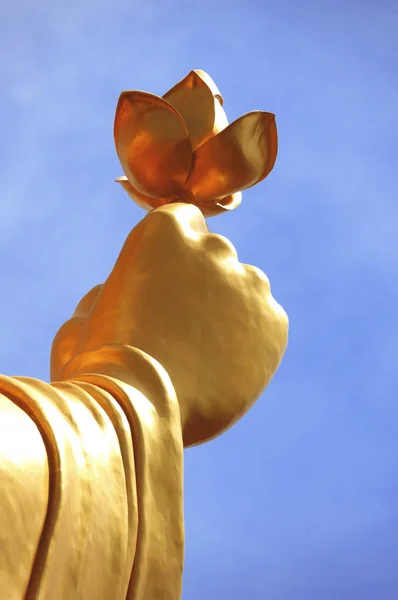 Estátua de Buda Dourado com mão segurando flor em um fundo azul céu (Da Lat, Vietnã ) — Fotografia de Stock