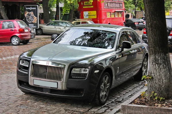 5 de agosto de 2012, Kiev, Rolls-Royce Ghost. Coche inglés en el fondo del autobús británico. El coche bajo la lluvia. Gotas de lluvia. Foto editorial . — Foto de Stock