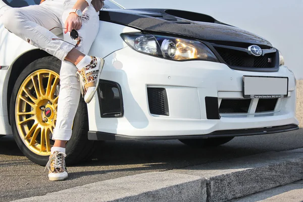 Kiev, Ucraina; 20 gennaio 2014. Subaru Impreza WRX STI. Ragazza in sneakers colorate e in pantaloni bianchi. Ragazza su sfondo auto. Auto e ragazza. Moda. Stile. Mi sintonizzo. Fast & Furious. Foto editoriale . — Foto Stock