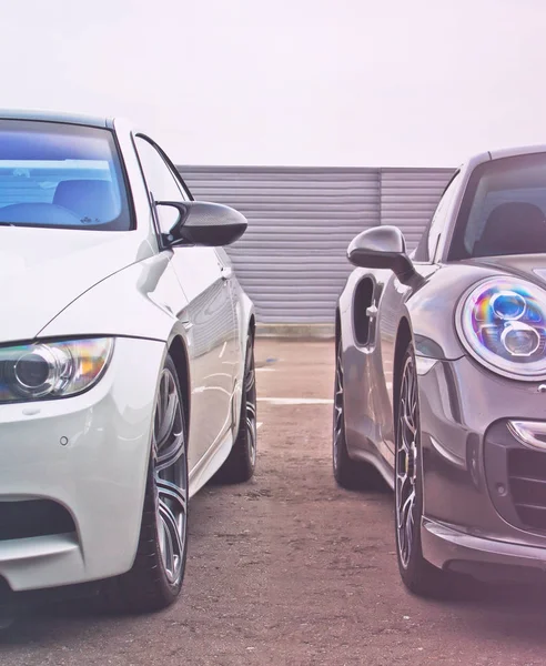 Parte dos coches en el fondo del cielo y la valla de metal. Dos coches de pie uno al lado del otro. Los coches blancos y grises. vehículos de lujo — Foto de Stock