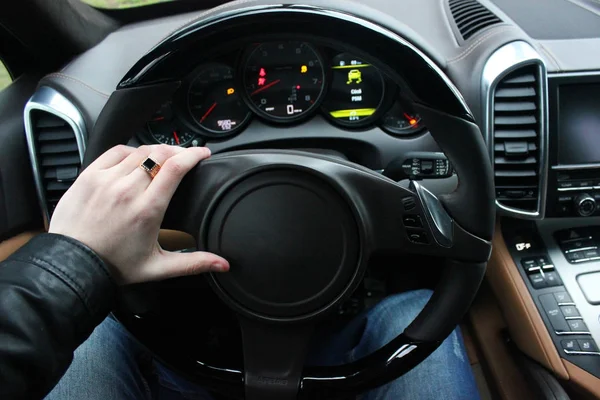 Un hombre sostiene el volante de un coche de lujo. Reloj de oro y un anillo en su mano —  Fotos de Stock