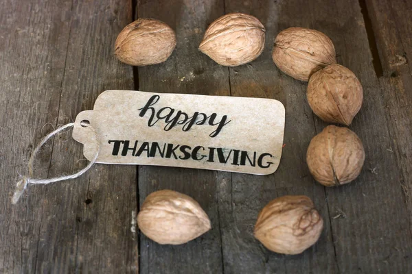 Надпись "С Днем Благодарения" и орехи на деревянном фоне — стоковое фото