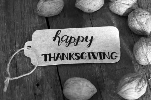 Die Inschrift "Happy Thanksgiving" und Nüsse auf einem Holzuntergrund — Stockfoto