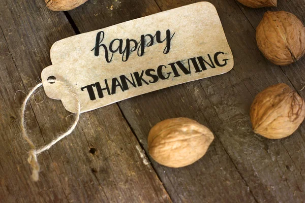 Die Inschrift "Happy Thanksgiving" und Nüsse auf einem Holzuntergrund — Stockfoto