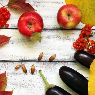 Ahşap bir arka planda sonbahar kompozisyonu. Elmalar, viburnum, patlıcan, yapraklar ve çiçekler