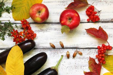 Ahşap bir arka planda sonbahar kompozisyonu. Elmalar, viburnum, patlıcan, yapraklar ve çiçekler