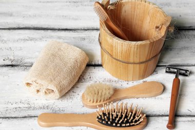 Banyo beyaz ahşap bir arka planda. Havlu, jilet, fırça ve tarak.