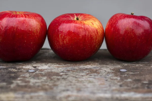 Trzy czerwone jabłka na szarym tle — Zdjęcie stockowe