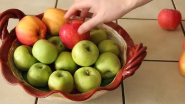El elmaları tabağa koyar.