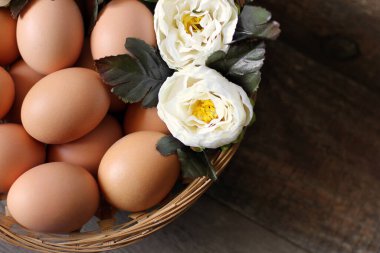 Tahta bir arka planda sepetteki yumurta ve çiçekler..