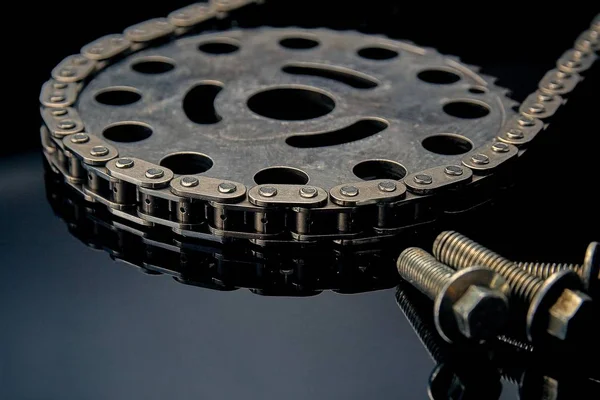 Rollenkette mit Ritzel auf dunklem Hintergrund. es wird auf Autos, Motorrädern, Fahrrädern und im Maschinenbau verwendet. — Stockfoto