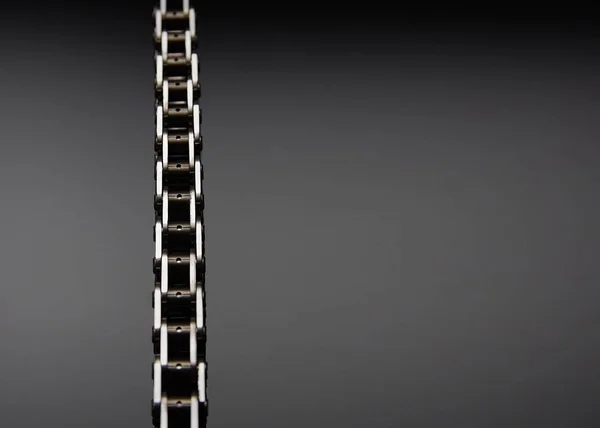 Roller chain with sprocket on dark background. It is used on cars, motorcycles, bicycles and in mechanical engineering.