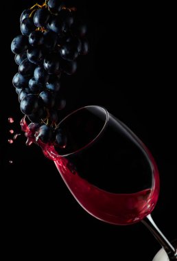 Red wine. Splashes of grapes flow into a glass on a black background.. Isolated on black background. Border art design