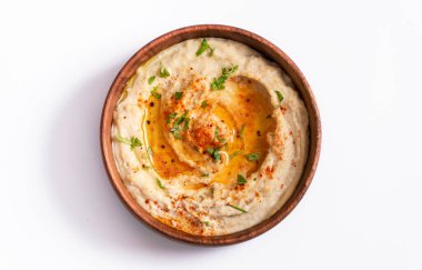 Zeytinyağlı ev yapımı humus, ahşap bir kasede otlar ve kırmızı biber. beyaz arkaplan.