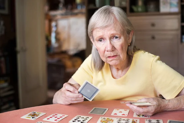 Беспокойная женщина играет в карты за столом — стоковое фото