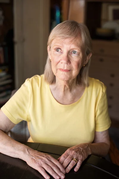 Ernstige senior vrouw aan tafel — Stockfoto