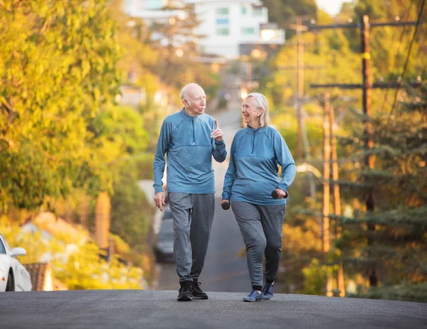 Senior couple walking along street on hill — Stock Photo, Image
