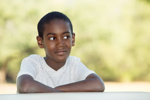 Grinning boy con le braccia piegate a tavola — Foto Stock