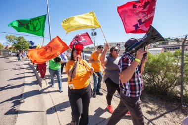 Marchers with colorful flags at border protest clipart