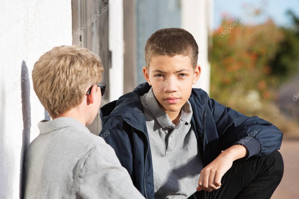 Male teen with serious expression listening to friend