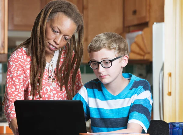 Child doing homework with foster parent in kitchen — Stock Photo, Image
