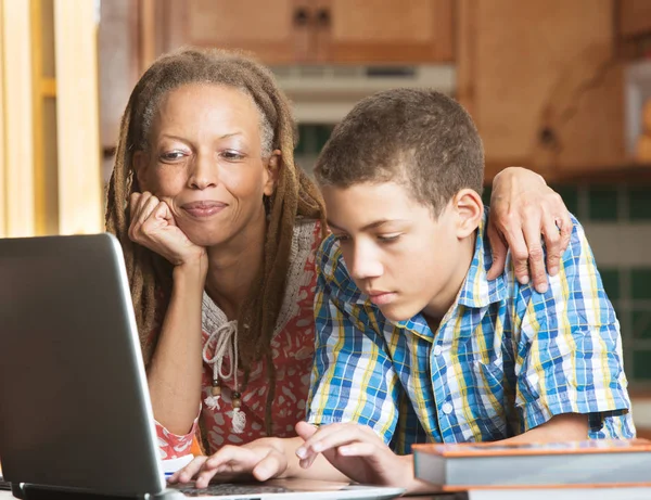 Mor och tonåring son jobbar i kök på laptop — Stockfoto