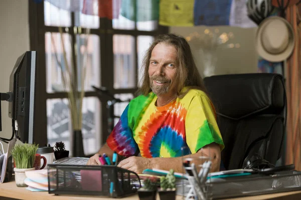 Homme souriant aux cheveux longs dans un bureau coloré — Photo