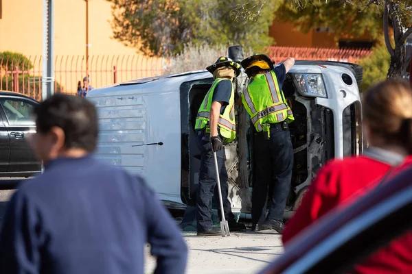 Omstanders kijken naar hulpverleners die een neergestort minibusje opruimen — Stockfoto