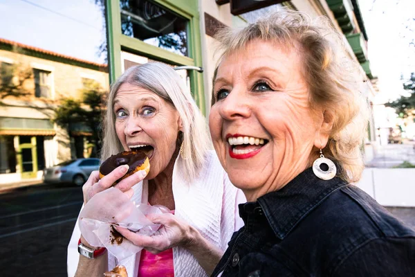 Женщины пожилого возраста едят пончики на открытом воздухе — стоковое фото