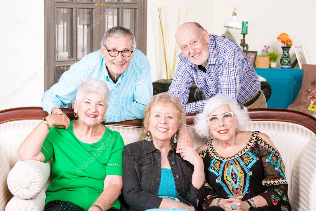 Five happy senior friends around an antique couch