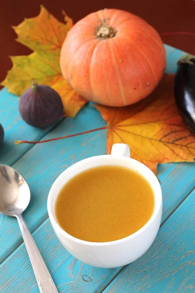 Soupe de citrouille en tasse blanche sur table bleue. Composition de la récolte . — Photo