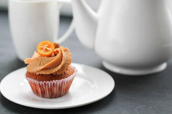 En tekanna, en kopp te och en karamell cupcake. — Stockfoto