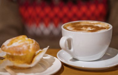 The cap of coffee with muffin/cake on the table in the cafe