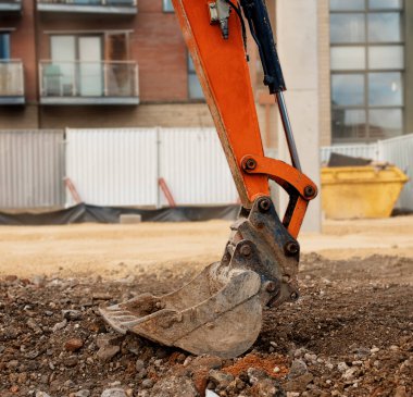 Yere yerleştirilmiş turuncu bir kazıcı kovasını kapat.  