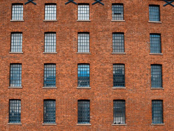 Facade / front of an old factory building made of red brick with a lot of vintage windows