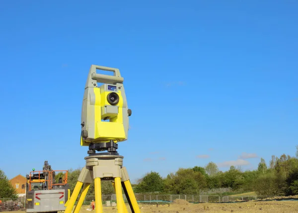 Yellow equipment set out on tripod on building site against a cloudless blue sky. Construction site surveying engineering equipment, EDM, tachometer set out on tripod site ready for setting out.