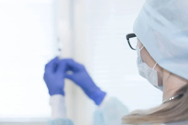 Medicine health background. Female doctor in mask and gloves holding a syringe with medicine, close-up