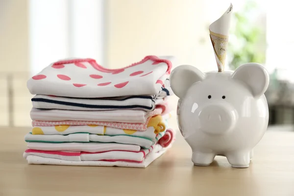 Pilhas de roupa de bebê e caixa de dinheiro — Fotografia de Stock