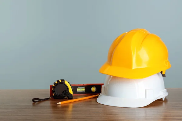 Bauwerkzeuge und Helme auf Holztisch — Stockfoto