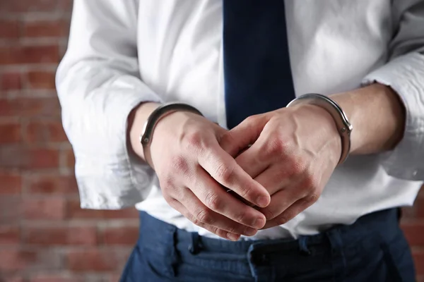 Man in handcuffs on brick wall background — Stock Photo, Image