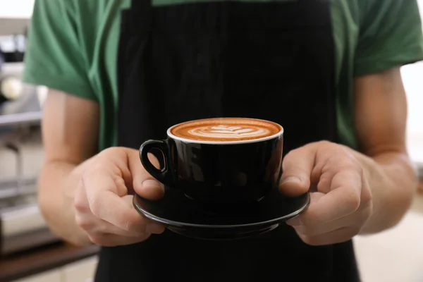 Человек держит чашку кофе с латте искусства — стоковое фото