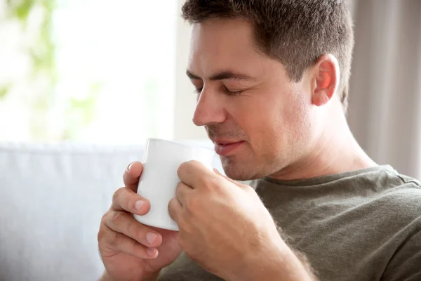 Handsome man sitting on couch with cup of coffee