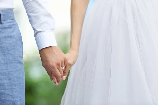 Bruid en bruidegom hand in hand samen buiten — Stockfoto