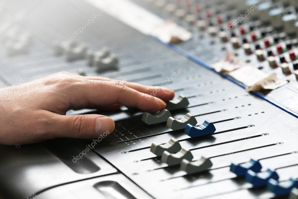 Hand on mixer in recording studio