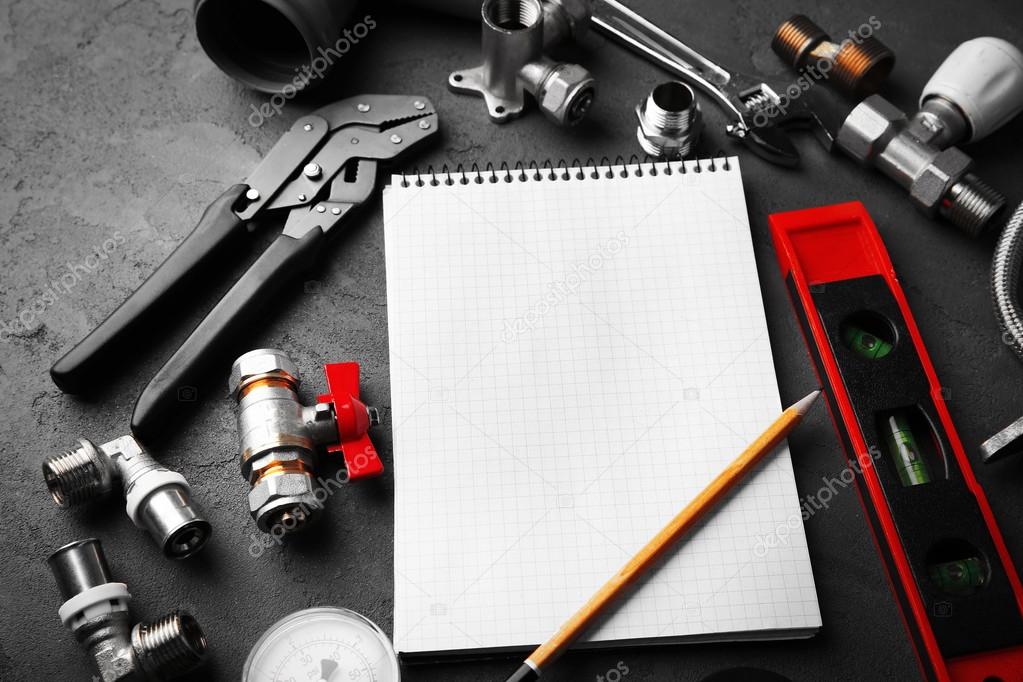 Notebook and plumber tools on concrete structure background