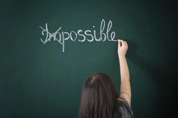 Little girl transforming word on chalkboard — Stock Photo, Image