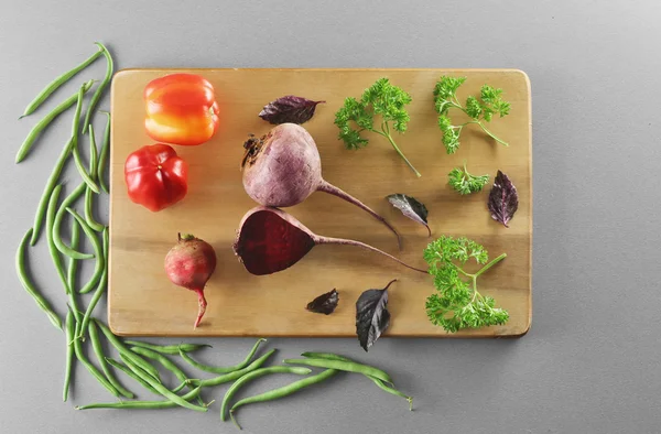Verse groenten op houten plank en grijze achtergrond — Stockfoto