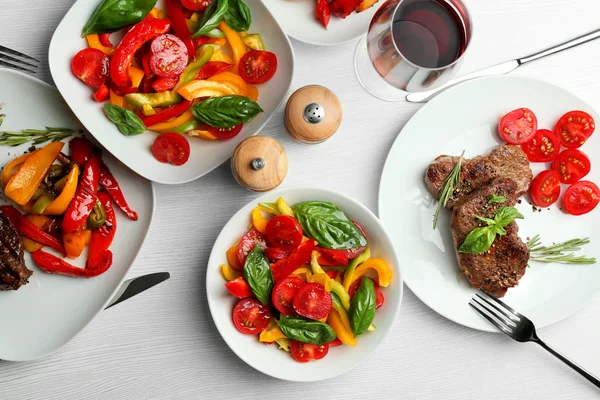 Steak savoureux avec salade de légumes et verre de vin sur la table — Photo