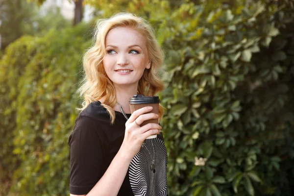 Menina bonita com xícara de café no fundo folhas verdes — Fotografia de Stock